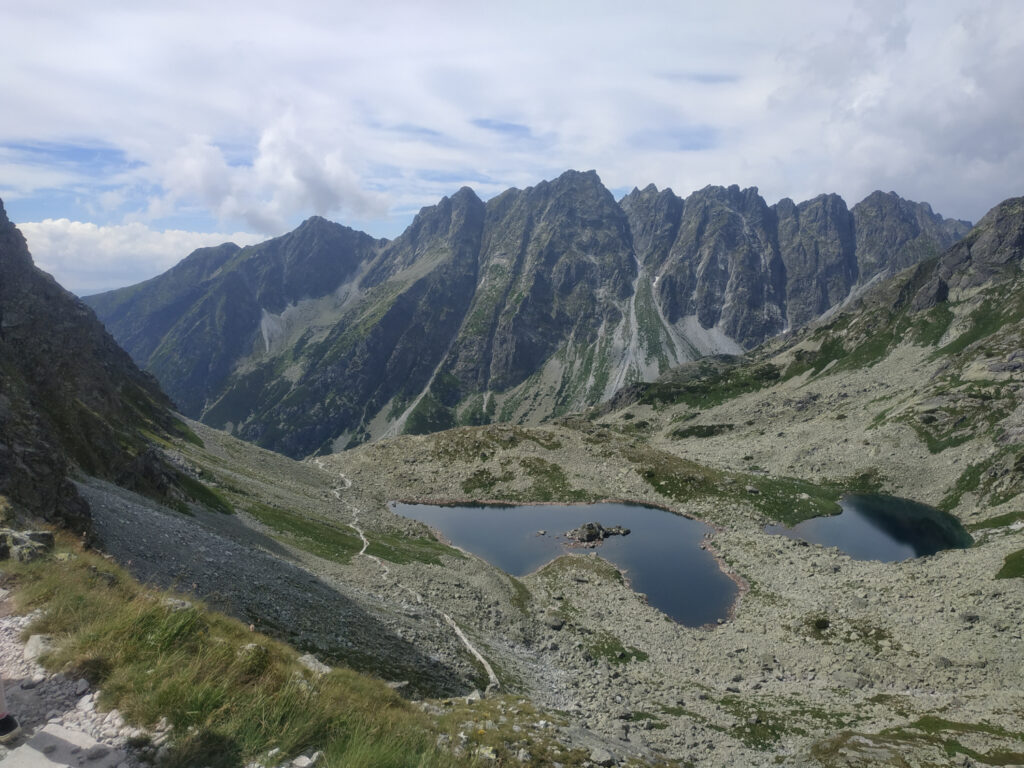 Tarty słowackie, w drodze na Rysy. Panorama na wysokie, skaliste szczyty słowackich Tatr. W dole dwa nieduże stawy.