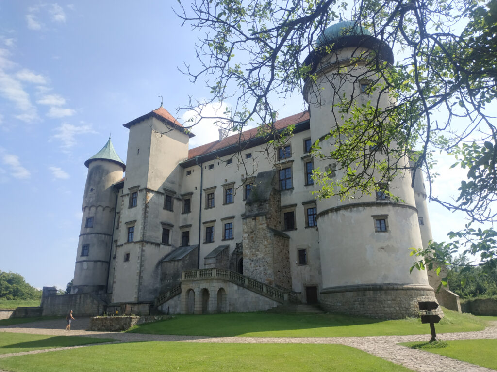 Zamek w Wiśniczu, widok od przodu. Dwie okrągłe wieże po bokach, na środku schody i wejście